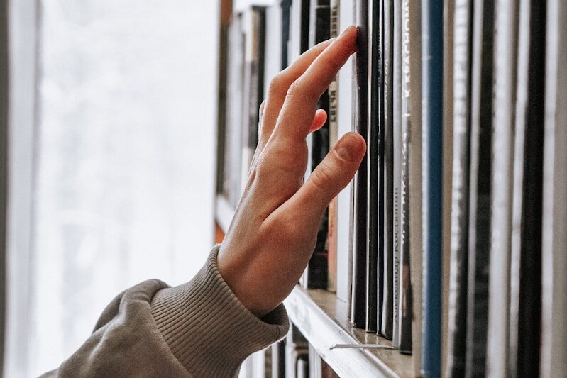 hand reaching for books on shelf